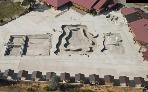 An aerial view showing an outdoor area under construction with pools and structures.