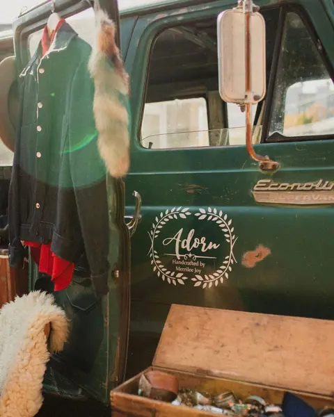 A close-up view of a green vehicle with a logo and clothing hanging on the door.