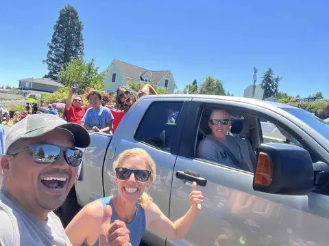 A group of people smiling in and around a pickup truck during an event.
