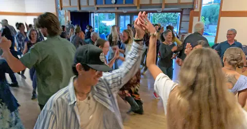 People dance together inside a bright hall.