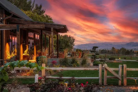 A wooden building with a porch overlooks a landscape during a vibrant sunset.