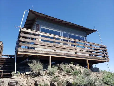 An exterior view of a fire lookout tower against a clear blue sky.