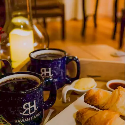 Mugs of coffee and pastries are served on a tray indoors.