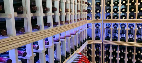 A large wooden wine rack filled with bottles of wine in a cellar.