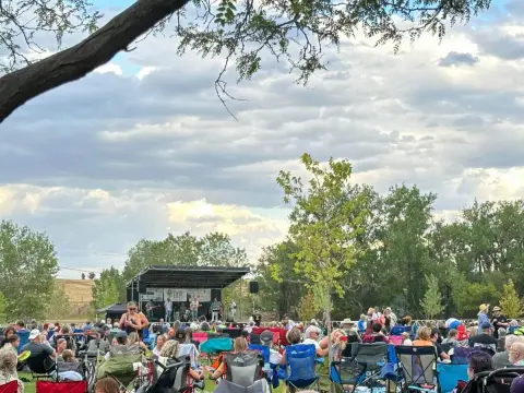 An outdoor concert performance with a crowd seated in lawn chairs.