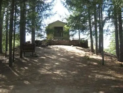A small building on a hilltop surrounded by trees.