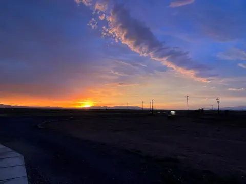 A sunset over a flat landscape with mountains in the distance.