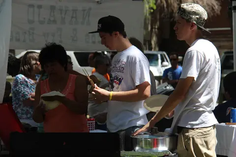 People preparing food at a stall outdoors.