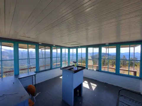 The interior of a fire lookout tower with windows showing a mountainous landscape.