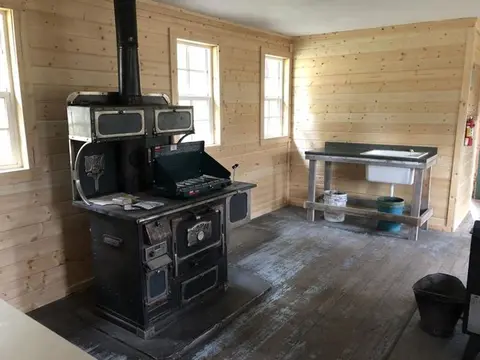 Interior of a rustic wooden room featuring a large stove and a sink.