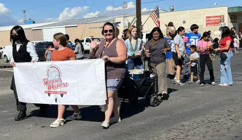 A group of people walk down a street carrying a banner in a parade.