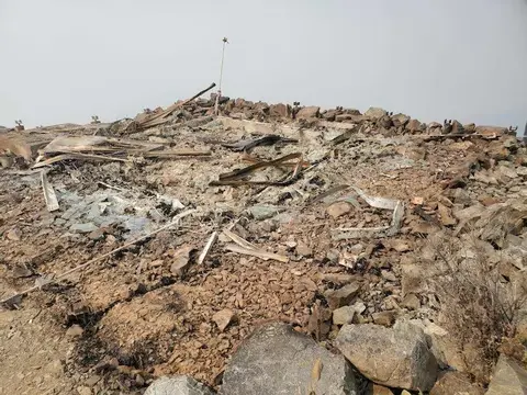 A rocky landscape showing ruins and debris scattered on a hilltop.