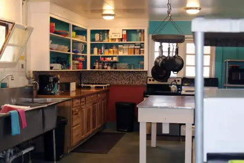 An interior view of a kitchen with open shelving, cabinets, and a center island.