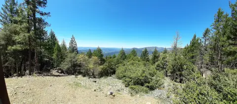 A scenic view of rolling hills and forests under a clear blue sky.