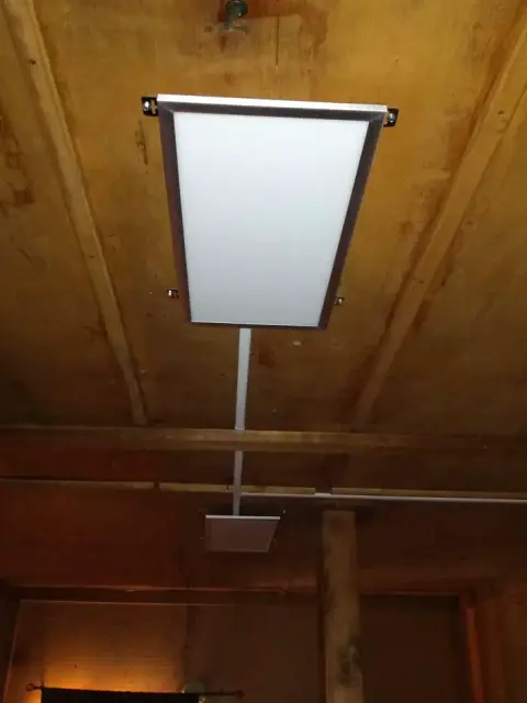 A rectangular light fixture is mounted on a wooden ceiling.