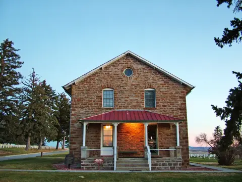 Exterior view of a historic stone building with a red porch roof and a small round window.