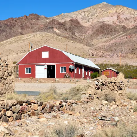 A red building stands in a desert landscape with mountains in the background.