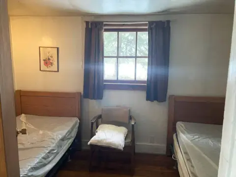 A bedroom with two twin beds and a window between them.