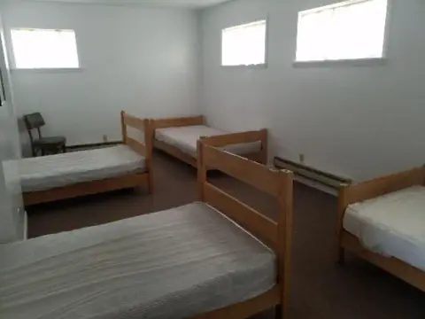 An interior shot of a dormitory-style room with several wooden beds.