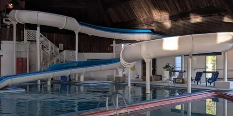Indoor swimming pool with water slides inside a wooden building.