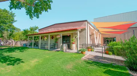 Exterior view of a building with a porch, lawn, and shade sails.