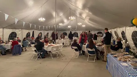 People seated at tables inside a decorated large tent.