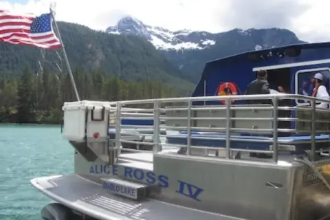 A view of the back of a boat on a lake with mountains in the background.