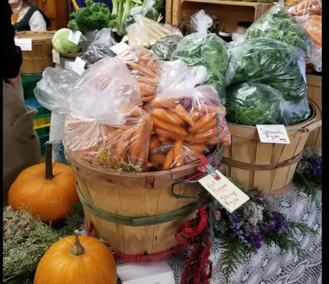 A display of fresh vegetables in wooden baskets at a market.
