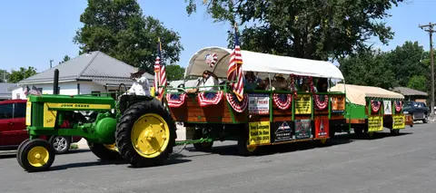 A decorated wagon pulled by a tractor during a parade.