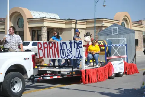 A parade float with people and a model cow.