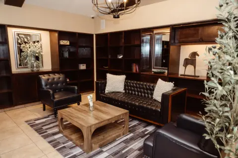 A photo of a modern interior lounge with dark leather couches and bookshelves.