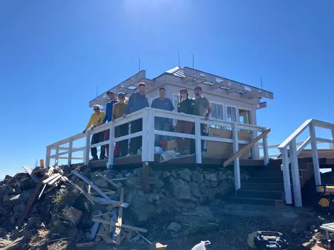 A group of people posing on the deck of a building under a bright blue sky.
