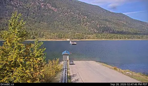 A boat on a body of water near a boat ramp with mountains in the background.