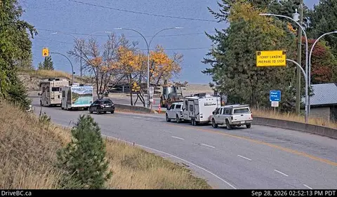 Vehicles driving on a road near a body of water.