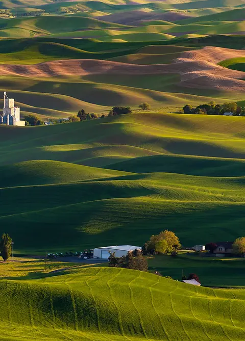 A high-angle view shows rolling green hills with farms and buildings nestled in the valleys.