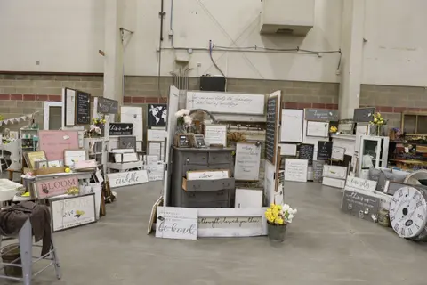 A display of home decor and wooden signs inside a large building.