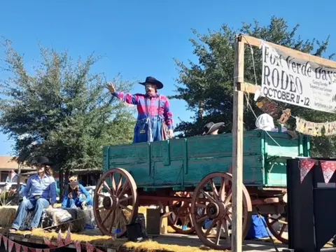 People dressed in western wear on a horse-drawn wagon float during an event.