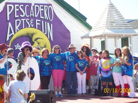 A group of people standing on a stage outdoors in front of a banner.