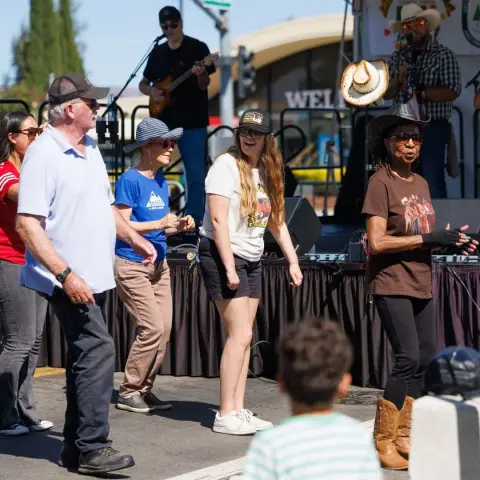 People dance in front of a stage with musicians.