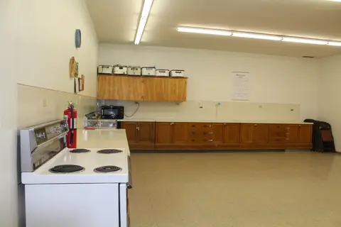 A large kitchen with a white stove and wooden cabinets along the wall.