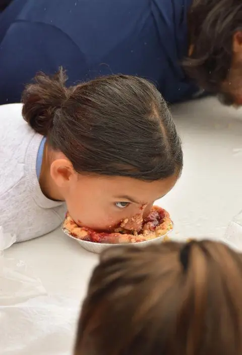 A young girl participates in a pie eating contest.