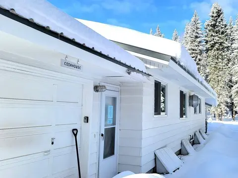 Exterior view of a white building covered in snow with a small sign above the door.