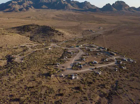 An aerial view of a campground in a desert landscape with mountains in the background.