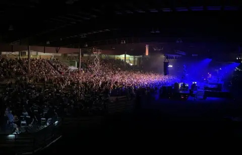 A large crowd gathers inside an indoor arena for a concert event.