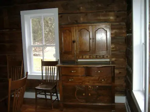 An interior shot of a room with log walls and a wooden cabinet.