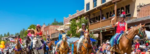 People ride horses down a street in a parade.