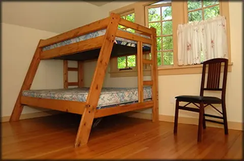 A wooden bunk bed and a chair inside a room.