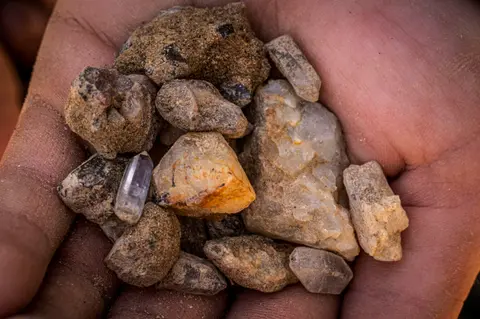 A person holds a handful of rocks and crystals.