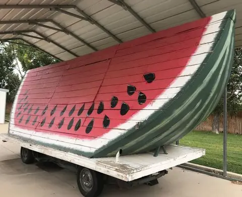 A large wooden float painted to look like a watermelon slice on a trailer.