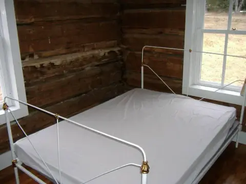 A bed inside a rustic log cabin room.